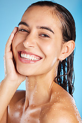 Image showing Face portrait, skincare shower and woman in studio isolated on a blue background. Water splash, beauty and happy female feeling fresh after bathing, cleaning and washing for healthy skin and wellness