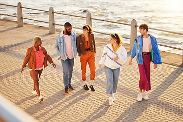 Image showing Diversity, friends and walking seaside, talking and break in summer holiday, bonding and conversation. Multiracial, men and women on promenade, discussion and vacation with sunshine or relax together