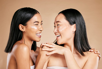 Image showing Laughing, beauty and excited women with cream for face isolated on beige studio background. Wellness, smile and Asian model friends with sunscreen for love of cosmetics and dermatology on a backdrop