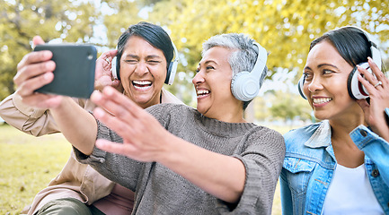 Image showing Senior woman, friends and phone laughing with headphones listening to music or watching comedy movie in the park. Group of happy elderly women enjoying funny series or 5G connection on smartphone