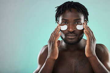 Image showing Skincare, eye pads and portrait of a black man in studio for healthy, cosmetic and natural face routine. Health, wellness and African guy with a facial treatment by blue background with mockup space.