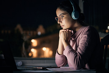 Image showing Laptop, night and music with a student woman in her home for learning, education or development using the internet. Computer, research and elearning with a female pupil studying late in a dark house