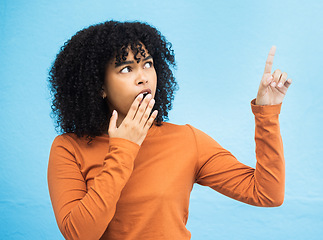 Image showing Black woman, surprise face and pointing in studio for news, announcement or gossip notification by blue background. Gen z girl, young african model and fashion with wow hand sign for hearing secret