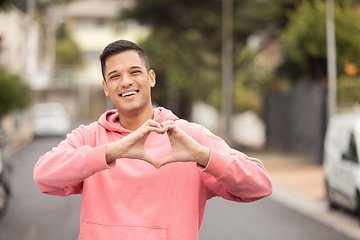 Image showing Portrait, hands and heart by man in city, happy and relax, travel and journey on blurred background. Face, traveler and emoji, hands and shape by handsome guy showing icon, love and smile for Mexico