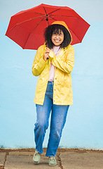 Image showing African woman, smile and umbrella by wall with excited face, rain and fashion raincoat in funny moment in city metro. Gen z girl, winter or comic laughing for weather, walk or urban outdoor adventure