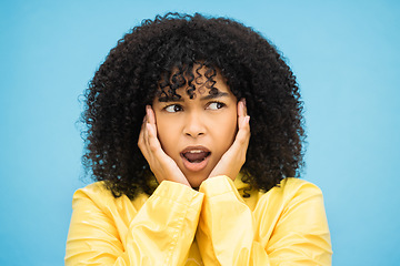 Image showing Black woman, afro or shocked face on isolated blue background in raincoat weather change, rainfall or rain. Model, person or surprised student with hands on cheeks in wow, emoji or scared expression