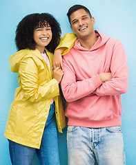 Image showing Couple of friends, portrait or bonding on isolated blue background in fashion, trend or cool style clothes. Smile, happy man or black woman with afro hair, arms crossed or weather raincoat protection