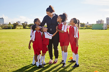 Image showing Girl, soccer group and field with coach, team building hug and solidarity at sport training. Female kids, sports diversity and happy with friends, teamwork and football coaching with mentor woman