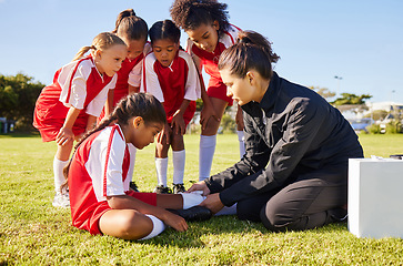 Image showing Sports, injury and children soccer team with their coach in a huddle helping a girl athlete. Fitness, training and kid with a sore, pain or muscle sprain after a match on an outdoor football field.