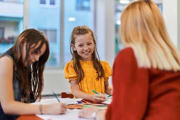 Image showing Creative kids during an art class in a daycare center or elementary school classroom drawing with female teacher.