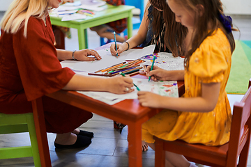 Image showing Creative kids during an art class in a daycare center or elementary school classroom drawing with female teacher.