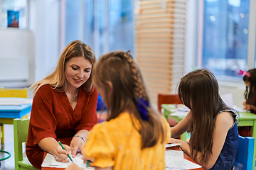 Image showing Creative kids during an art class in a daycare center or elementary school classroom drawing with female teacher.