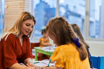 Image showing Creative kids during an art class in a daycare center or elementary school classroom drawing with female teacher.