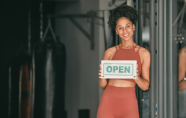 Image showing Fitness, portrait or personal trainer at gym with an open sign for workout exercises or training. Manager, happy or healthy black woman with a friendly smile holding a board to welcome exercising