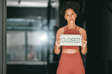 Image showing Fitness, portrait or personal trainer at gym with a closed sign for workout exercises or training. Manager, bankruptcy or serious black woman holding a board to stop exercising in empty health club