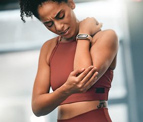 Image showing Elbow, pain and fitness with a sports black woman in the gym with a sore joint from an exercise workout. Injury, training and health with a young female athlete struggling with a hurt arm or muscle