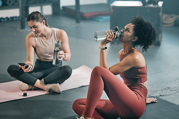 Image showing Fitness, relax and drinking water with women in gym for workout, exercise and cardio. Training, wellness and sweating with friends resting on floor of sports center for health, fatigue and tired