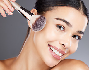 Image showing Face, beauty makeup and woman with brush in studio isolated on a gray background. Portrait, aesthetics and happy young female model apply powder, foundation or cosmetics product for skincare wellness