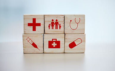 Image showing Health, insurance and wooden blocks on empty table in grey studio background for safety or security. healthcare logos, medicine and abstract block toys in a hospital design or clinic for medical care