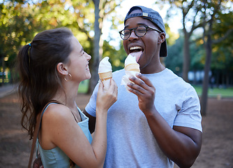 Image showing Interracial, ice cream or couple of friends in a park walking on a fun romantic date in nature bonding together. Romance, relaxed black man and happy woman loves eating a snack on a holiday vacation