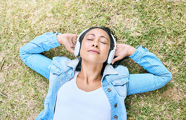 Image showing Music, headphones and woman relax in a park, peace and zen from above, content and calm. Podcast, earphones and girl resting while listening to audio for wellness, stress free and chilling on grass