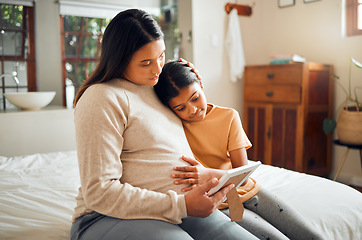 Image showing Pregnant mom and child look at a picture frame together in the bedroom of their modern house. Sad, emotional and mother with pregnancy holding her girl kid while looking at a photo on the bed at home