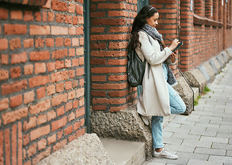 Image showing Woman, student and tablet relaxing on brick wall writing, design or doing research in the city. Female university learner working on touchscreen with wireless pen or tech in a urban town