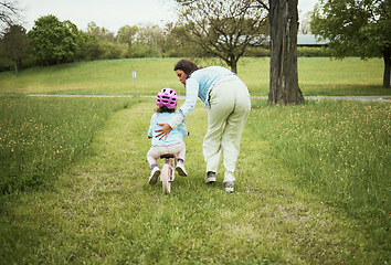 Image showing Mother, girl and learning with bicycle in park with love, bonding or happy by grass field on holiday. Mama, kid and teaching, cycling and bike on outdoor adventure, woods or backyard garden in nature