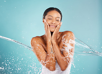 Image showing Water splash, skincare and woman in a studio with a beauty, cosmetic and natural face routine. Health, wellness and female model with a fresh organic facial treatment isolated by a blue background.