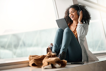 Image showing Travel tablet, music headphones and black woman streaming radio or podcast. Technology, relax and happy female with touchscreen for social media app, networking and internet browsing at airport lobby