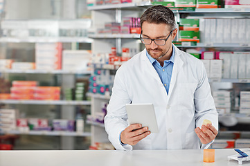 Image showing Pharmacist man, shop and reading with tablet, medicine, pills and counter for health, medication or sales. Medical professional, pharma expert and mobile digital tech in pharmacy with wellness app