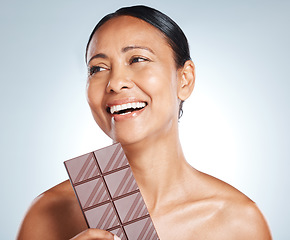 Image showing Chocolate, smile and senior woman thinking of health isolated on a blue background in studio. Food, happy and face of an elderly model with an idea for candy, sugar snack and sweets on a backdrop