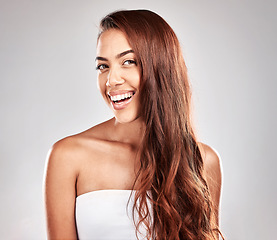 Image showing Hair care, beauty and portrait of a woman in studio for a keratin, brazilian or botox hair treatment. Happy, smile and female model with a wavy, long and shiny hair style isolated by gray background.