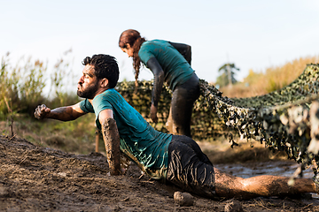 Image showing Athletes crawling through mud