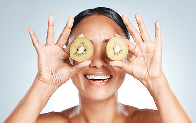 Image showing Skincare, beauty and woman with kiwi on eyes for vitamin c facial detox and smile on studio background. Healthy skin care, wellness and sustainability, organic luxurycleaning and grooming with frui