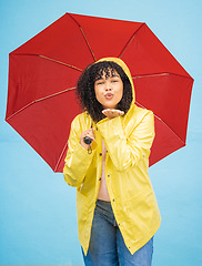 Image showing Portrait, black woman and umbrella in a city for kiss, travel and flirting on a solo trip against wall background. Face, blowing kiss and girl traveler relax in rainfall, excited and emoji gesture