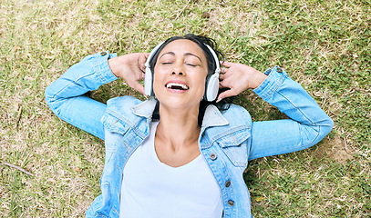 Image showing Music headphones, top view and woman relax at park outdoors. Peace, calm and happy, carefree and mature female streaming radio, podcast or audio song while relaxing or resting on grass in nature.