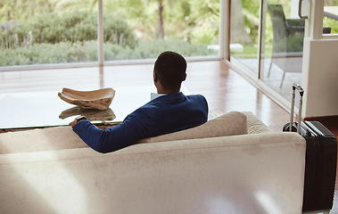 Image showing Thinking, immigration and vision of businessman on a couch or sofa in a hotel sitting looking at a window. Rear view, travel and back of professional corporate worker waiting in lounge or living room