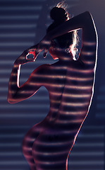 Image showing Sensual, blinds and woman posing in a studio with an alluring, sexy and seductive pose with light. Beautiful, slim and boy of a female model with a stripe pattern isolated by a dark black background.