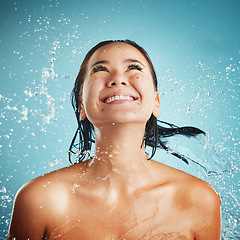 Image showing Woman, water splash and happy skincare or luxury body wellness treatment. Young Asian girl smile, beauty model and shower hydration or natural healthy cosmetic hygiene in blue background studio