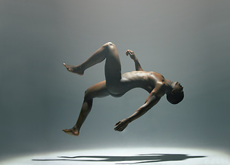 Image showing Nude, body and man in studio for art, levitating and creative, artistic against a grey background. Fine art, model and naked male floating, light and posing bare, falling and erotic art deco isolated