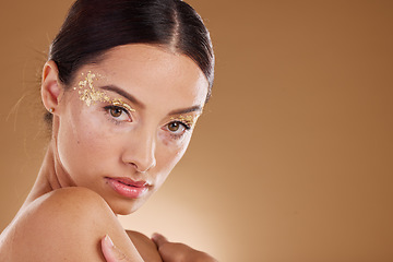 Image showing Gold makeup, woman and beauty portrait with model ready for cosmetic, wellness and spa. Brown background, studio and isolated young female person with mock up, cosmetics and glitter eyes alone