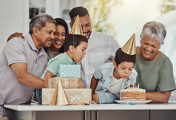 Image showing Birthday, celebration and twin children with family blowing the candles on a cake at their party. Happy, excited and kids with their parents and grandparents in the kitchen of their home to celebrate