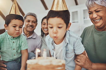 Image showing Kids, birthday cake and kid blowing candles at a house at a party with food and celebration. Children, celebrate event and family together in a kitchen with a smile and happiness with parent love