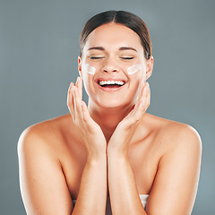 Image showing Woman apply cream for face, happy laugh and beauty, skincare and moisturizer isolated on studio background. Sunscreen, lotion and healthy skin with glow, wellness and facial treatment with happiness