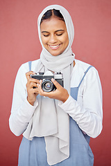 Image showing Muslim, hijab and photographer shooting a picture or photo with a retro camera isolated in a studio red background. Islam, Dubai and woman in scarf happy taking creative shots for photography