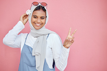 Image showing Woman, scarf and flower with peace sign and smile for beautiful casual fashion against pink studio background. Portrait of happy muslim female smiling in happiness and showing hand gesture on mockup