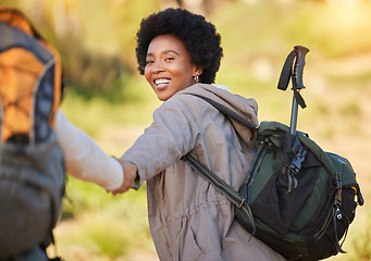 Image showing Black woman, holding hands and hiking with smile for travel, adventure or journey with partner in nature. Happy African American female helping friend on hike in support for trekking challenge