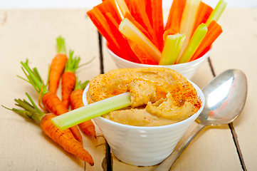 Image showing fresh hummus dip with raw carrot and celery