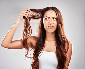 Image showing Woman, hair care and angry face in studio for luxury wellness, damaged hair loss or frustrated. Upset model, salon stress and messy hairstyle mistake, beauty problem or split end in grey background